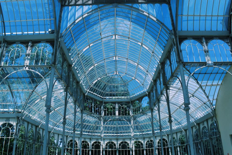 Interior view of a large Victorian-style glasshouse with ornate metal framework and arched glass panels. The structure features tall, decorative columns supporting the glass roof, allowing natural light to fill the space. The glass surfaces are clean and clear, with no visible dust or smudges, highlighting a well-maintained environment suitable for showcasing the importance of surface cleaning and maintenance in historic or commercial buildings. This setting exemplifies the need for professional cleaning to preserve the hygiene and appearance of large glass installations, aligned with services offered by crystalpalacecarpetcleaning.co.uk for deep cleaning and sanitisation. The ambient lighting creates a bright, airy atmosphere, emphasizing the importance of regular cleaning to maintain cleanliness and safety in such spaces.